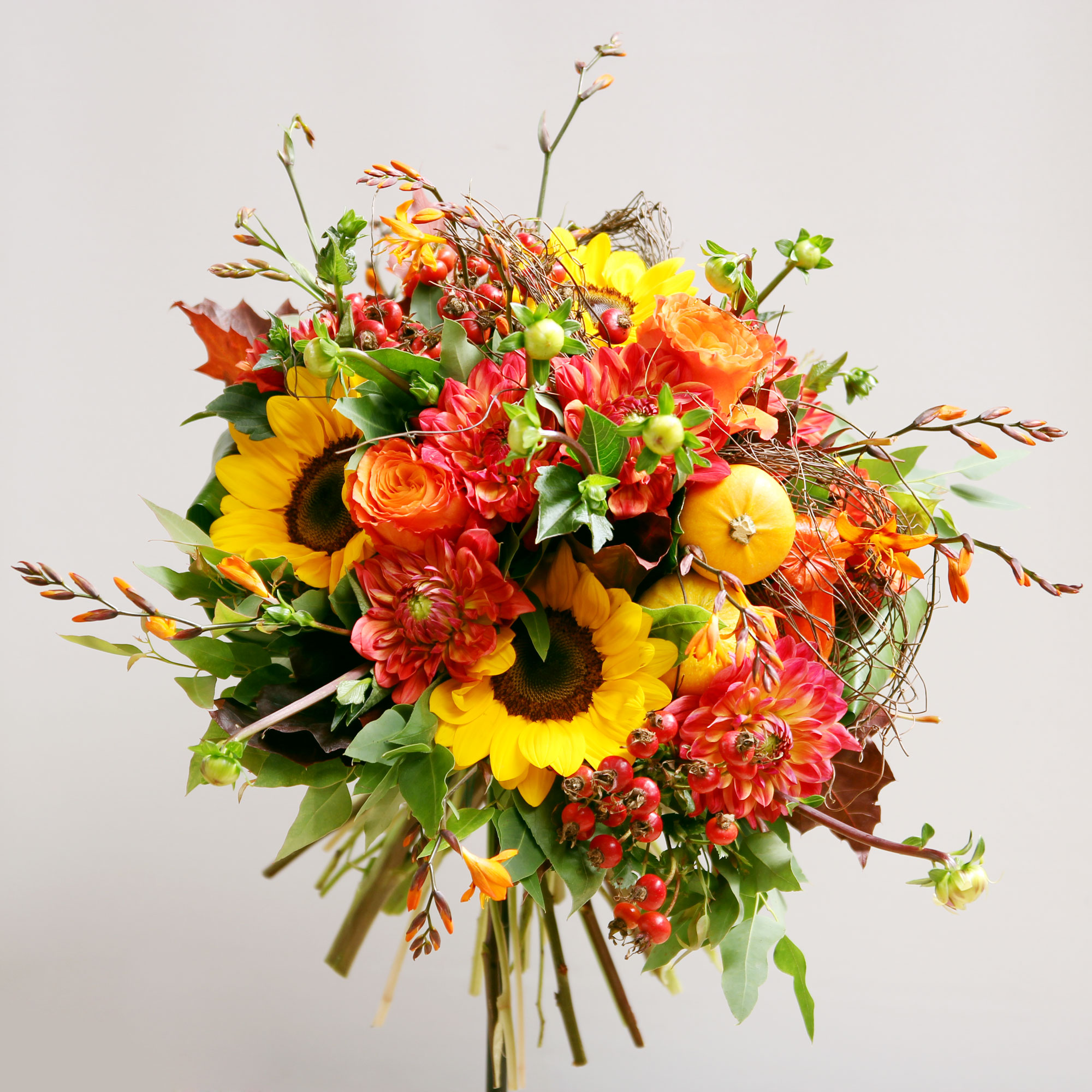 Bouquet de fleurs composé de tournesols, dahlias, crocosmias, baies de rose, roses.
