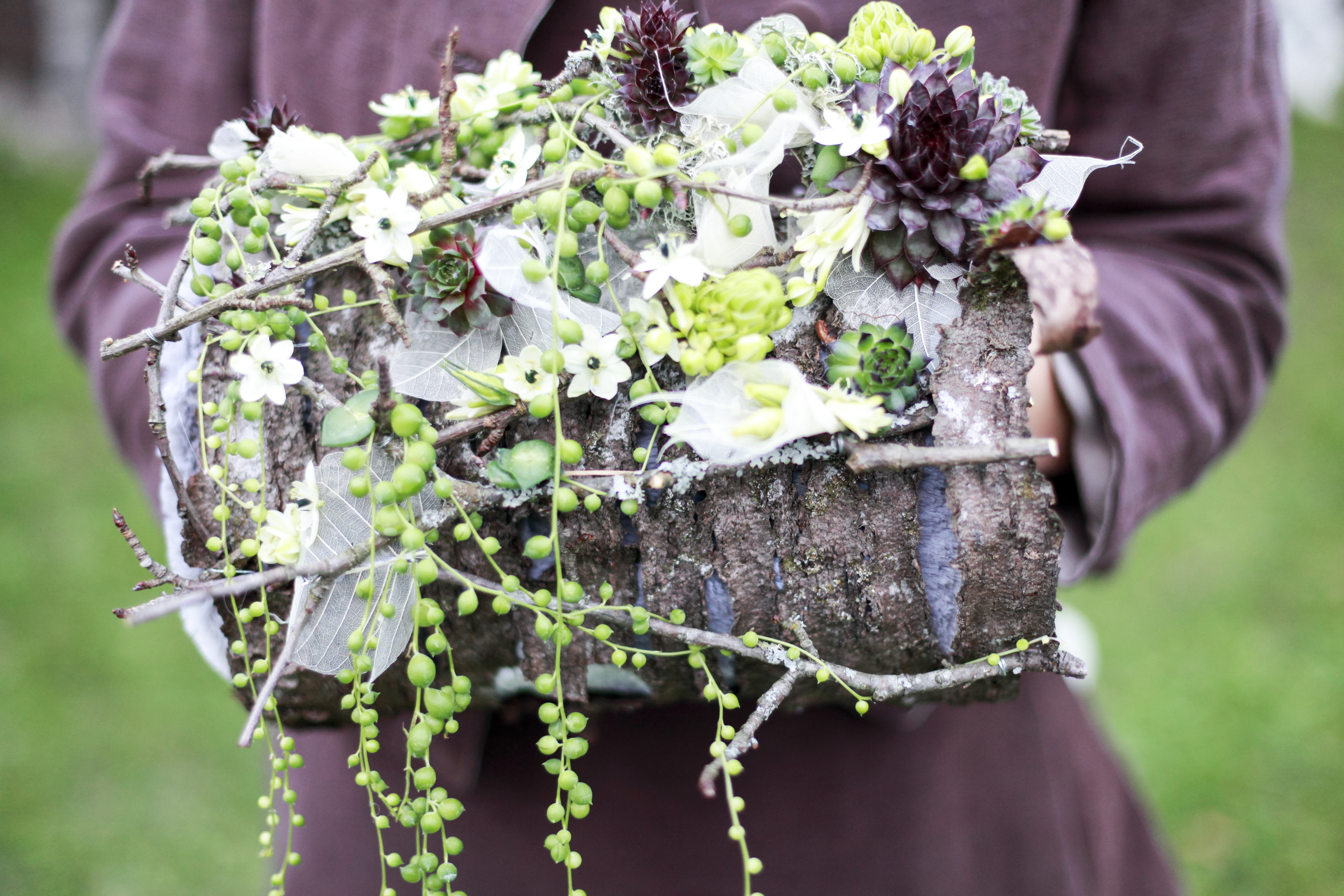 Le bouquet manchon est réalisé à partir d’écorce de bois, de petites plantes grasses et de fleurons d’ornithogalum arabica.